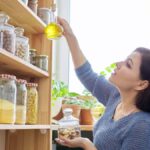 Woman choosing oil from a neat pantry