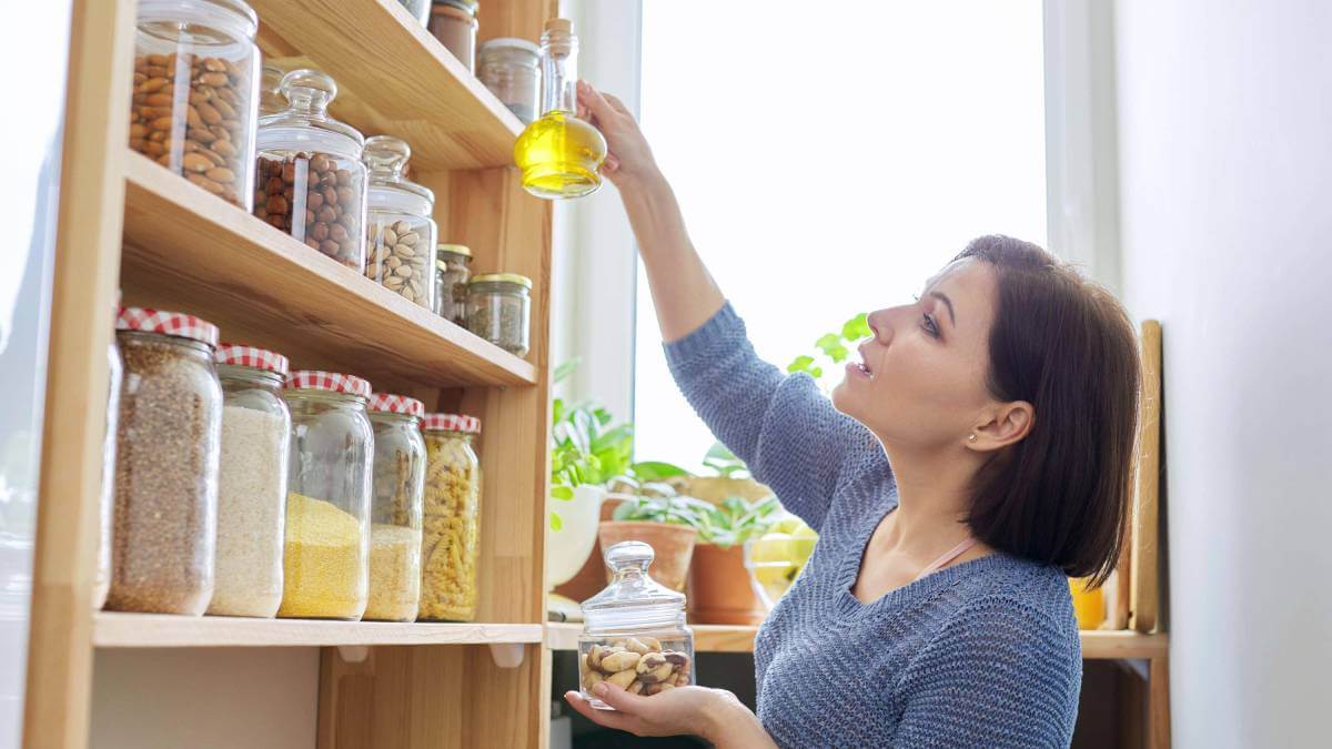 Woman choosing oil from a neat pantry