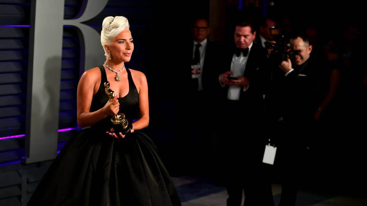 Celebrity in black dress holding an Oscar