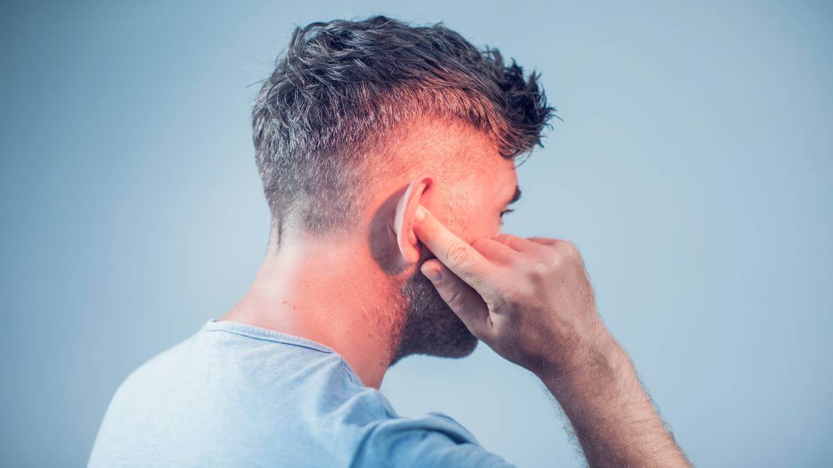 Man pressing his finger into his ear