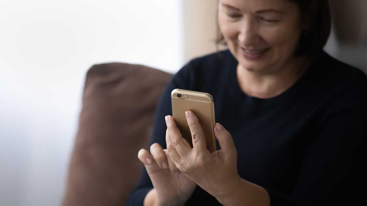 Happy older 60s woman using telehealth app on mobile phone
