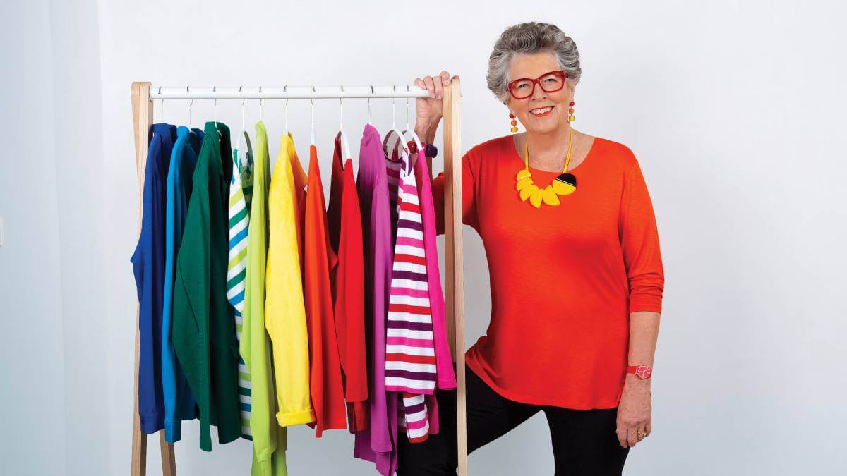 Prue Leith standing next to a rail of colourful clothes