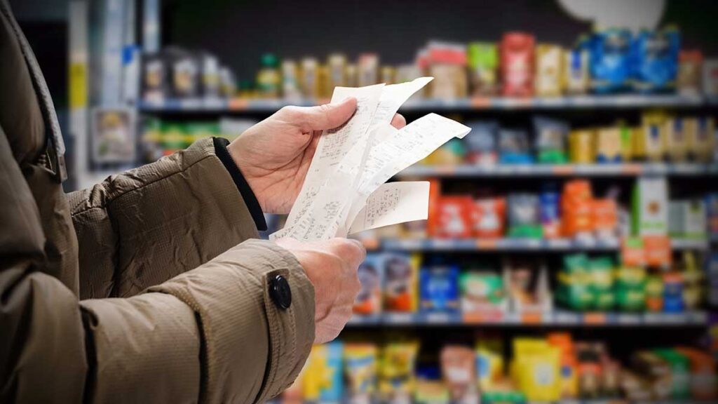 man concerned about rising inflation viewing receipts in supermarket