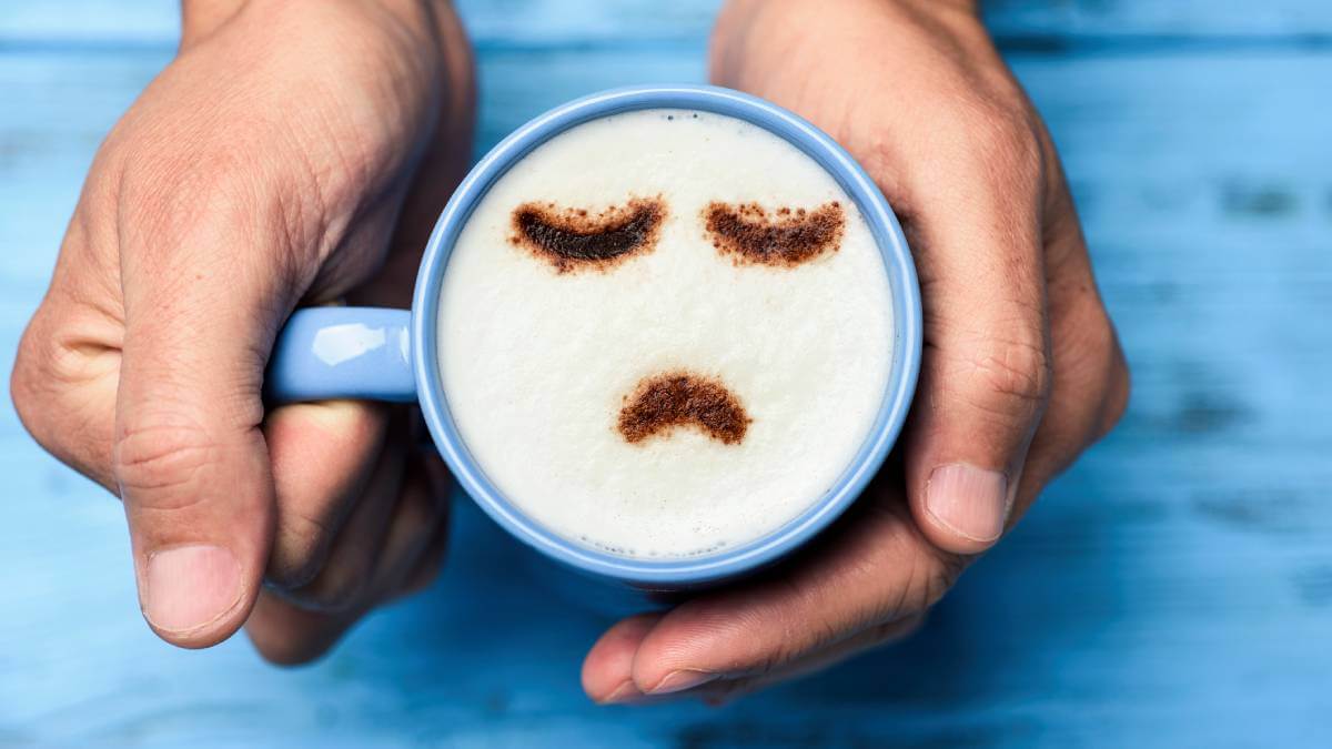 Cup of coffee with a sad face in the foam