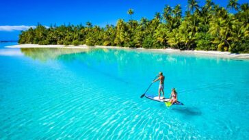 Two people paddle boarding on a bright blue ocean