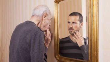 Old man looking at a younger version of himself in the mirror