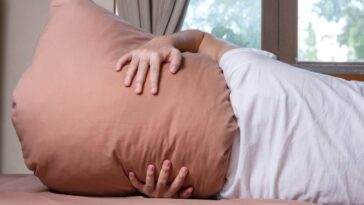Woman holding a pillow over her head