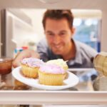 man taking cupcakes from fridge
