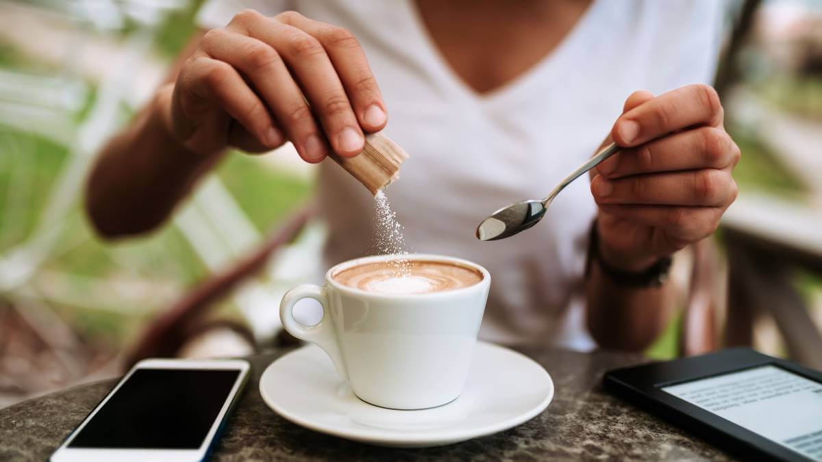 Woman pouring sugar in coffee