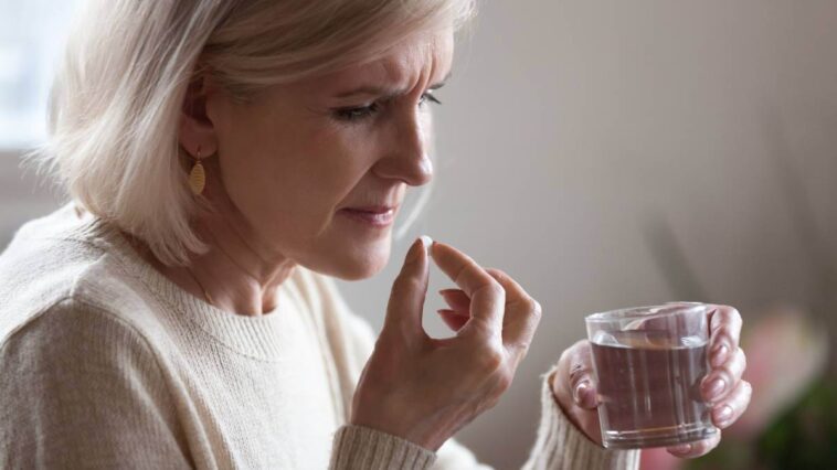 Woman taking a pill and not looking too happy about it