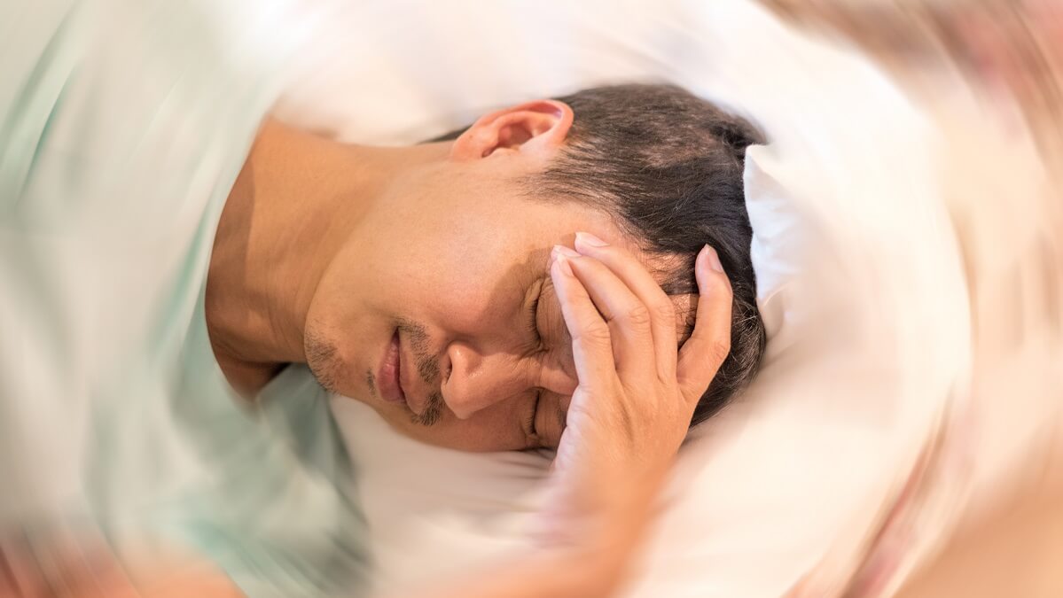 dizzy man lying in bed