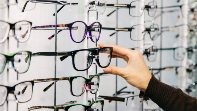 Hand choosing a pair of glasses from a display
