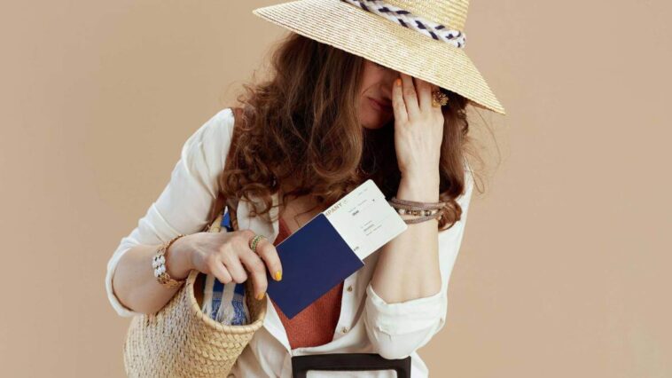 Woman holding a passport with a hand on her head