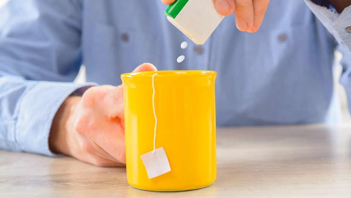man putting artificial sweetener in coffee