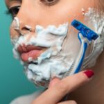 woman shaving face with razor