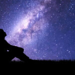 man sitting looking at night sky