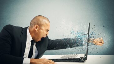 man punching laptop screen