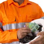 man wearing mining gear putting cash into mining helmet
