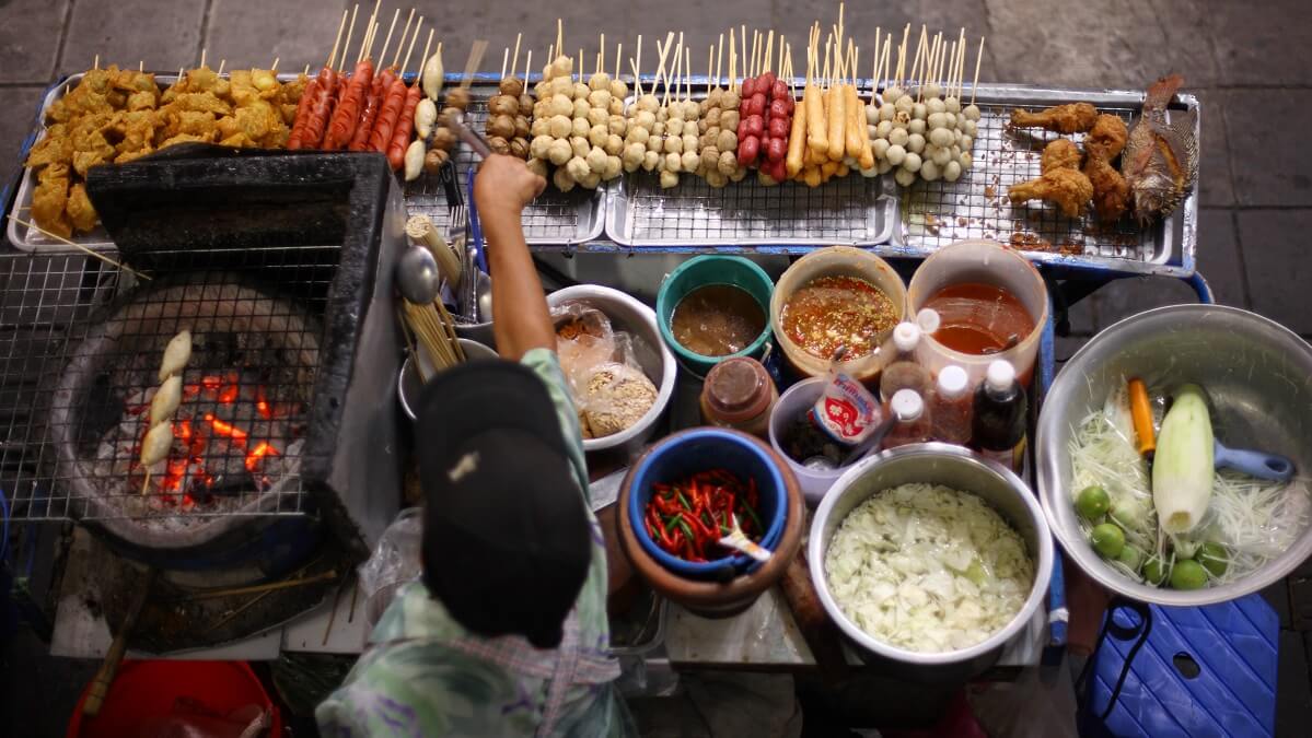 man cooking street food in thailand