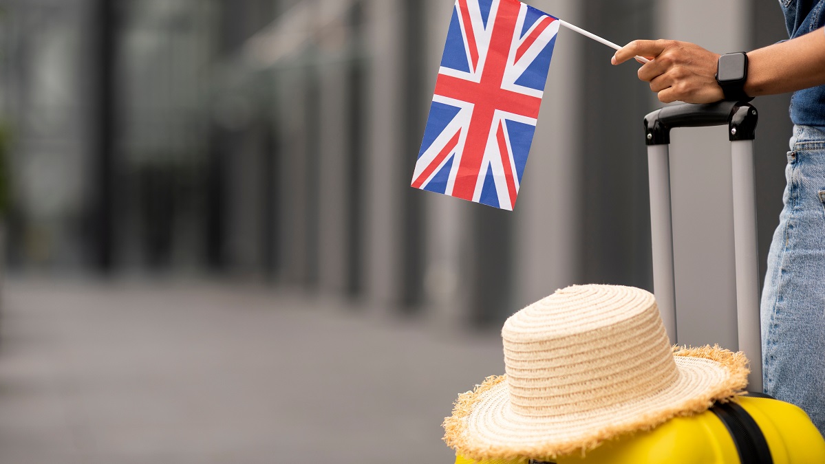 woman with suitcase holding mini UK flag
