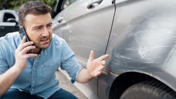 man examining scrape on car