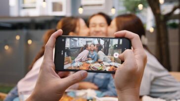 woman taking photo of family at dinner