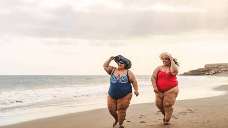 Two plus size women walking on the beach