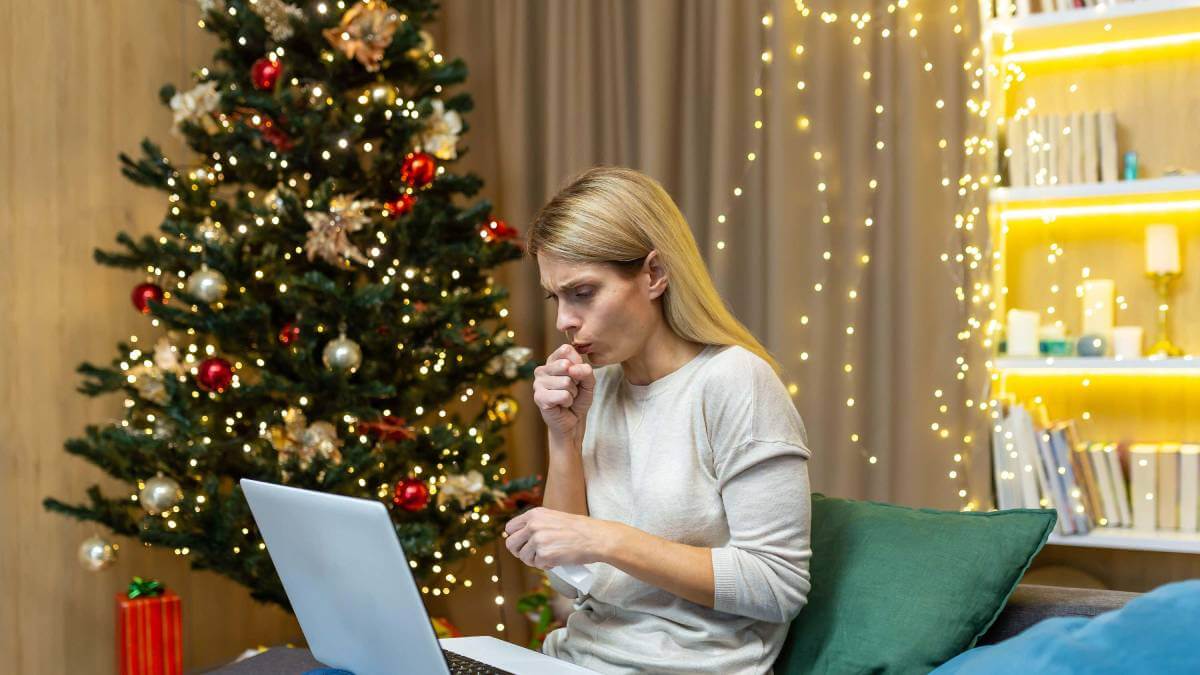Woman coughing in front of a Christmas tree