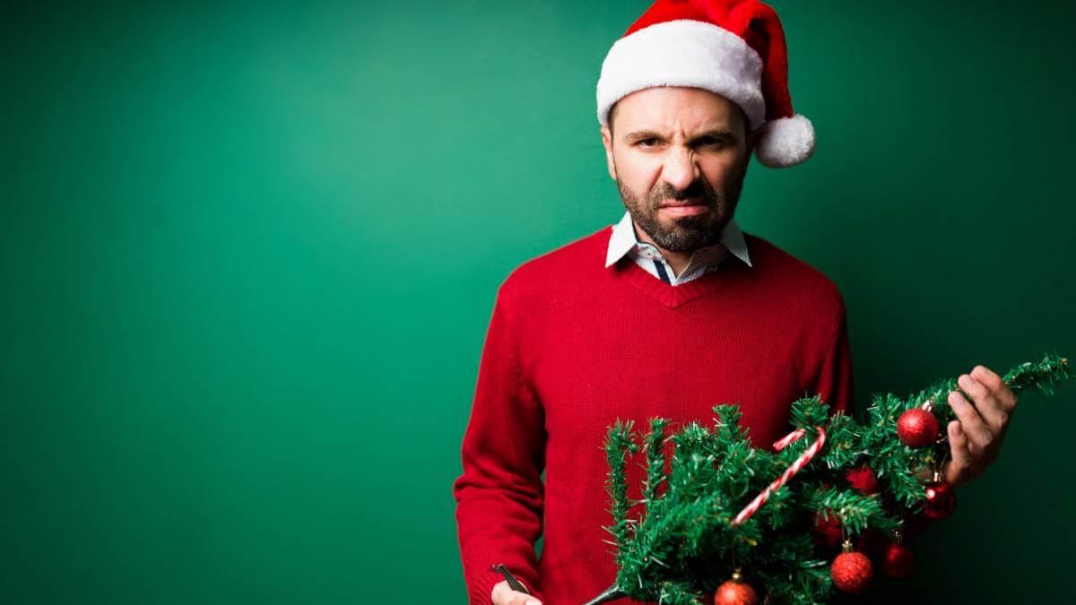 A man looking cranky with a Christmas tree