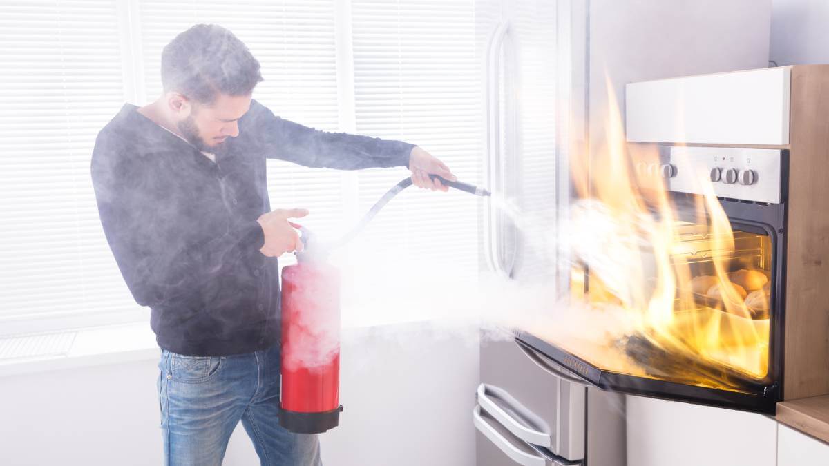 Man putting out a fire in the kitchen