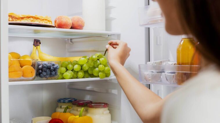 Woman choosing grapes from her fridge