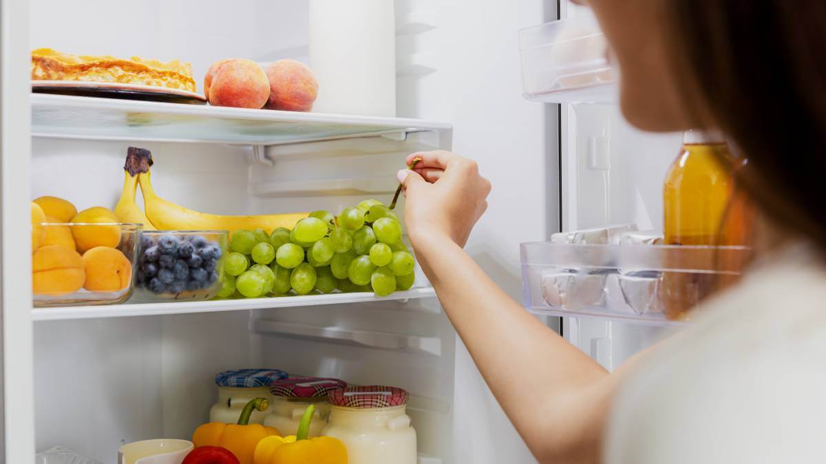 Woman choosing grapes from her fridge