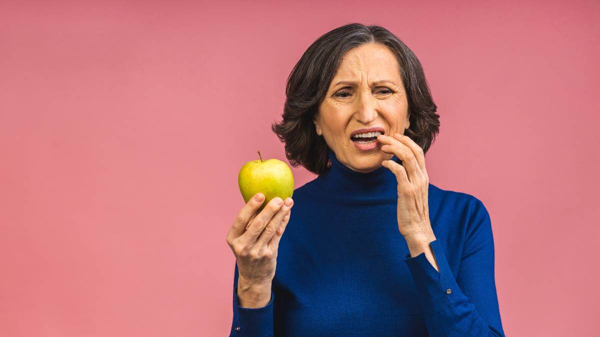 A woman with sore teeth after biting an apple