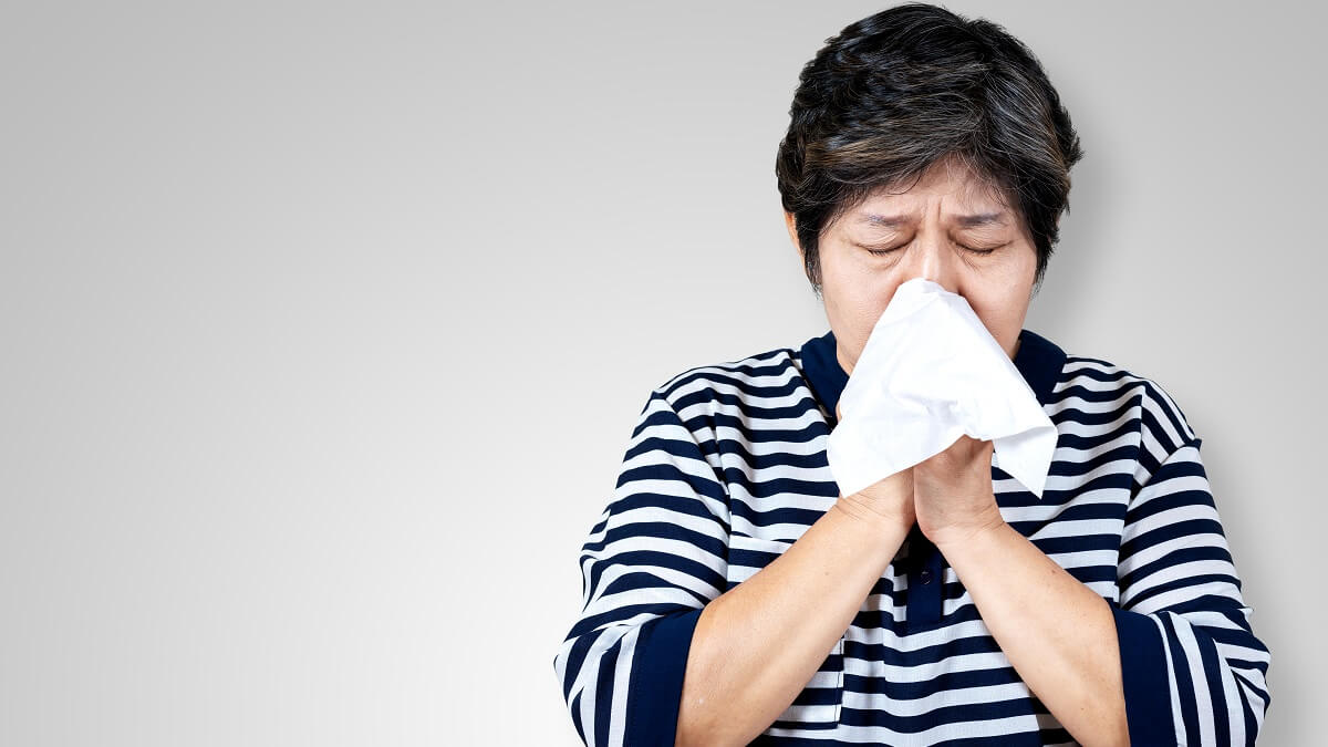 older woman sneezing into handkerchief