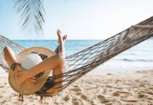 Happy traveler asian woman with white bikini relax in hammock on beach