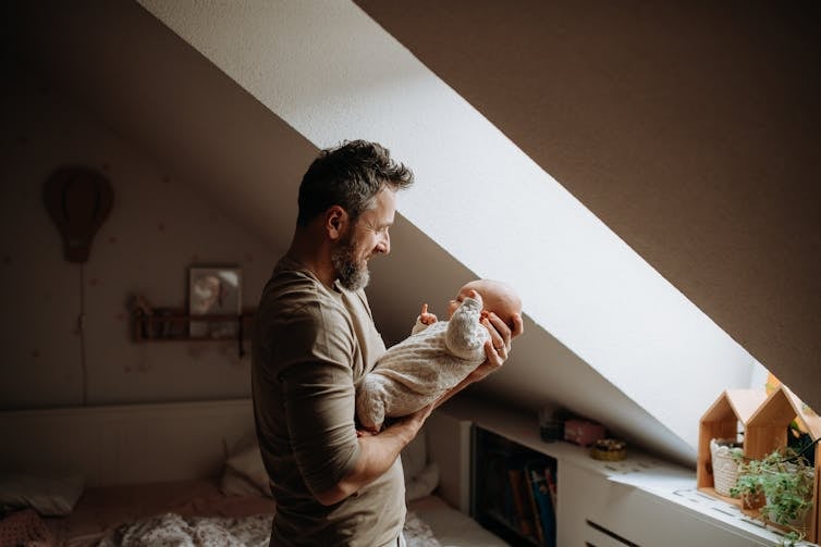 A young father lovingly holding his newborn.