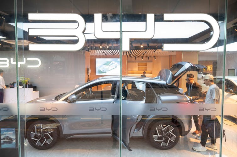 People look at an EV in a car dealership.