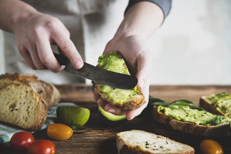 Person spreads avocado on toast.