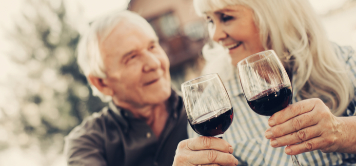 mature couple holding wine-filled glasses