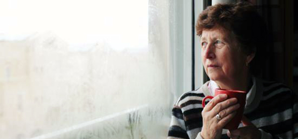 A woman approaching retirement age looks out the window with uncertainty
