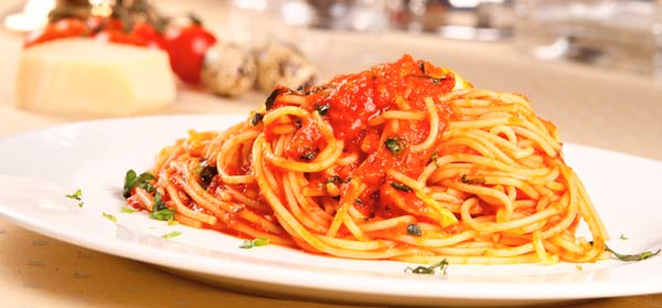 bowl of spaghetti marinara with basil on table