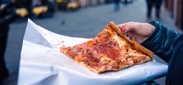 Close up of womans hand holding big slice of pizza on holiday