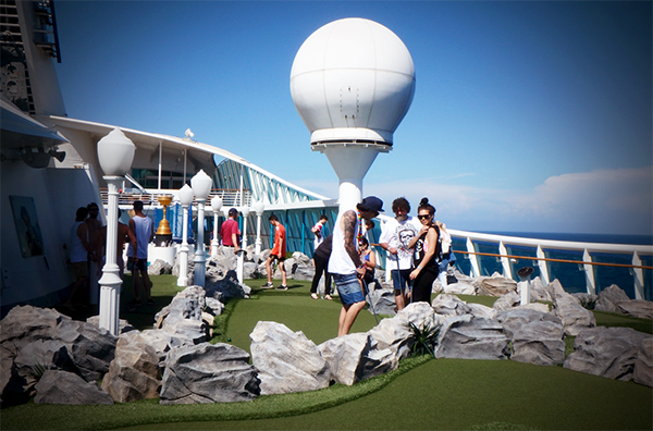 a group of people playing minigolf on the sports deck of the explorer of the seas superliner