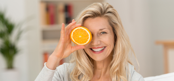 Happy blonde woman with healthy eyes holding oranges