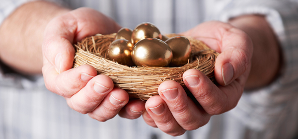 Man's hands holding nest full of gold pension eggs