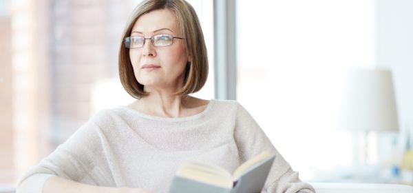 Mature woman looking out of the window with book