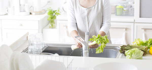 older lady washing vegetables in her very white kitchen