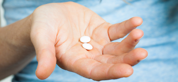 Womans hand holding asprin tablets